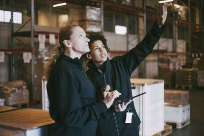 Businesswoman gesturing while discussing with female colleague at warehouse