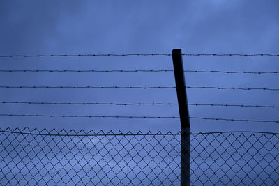 Low angle view of chainlink fence against blue sky