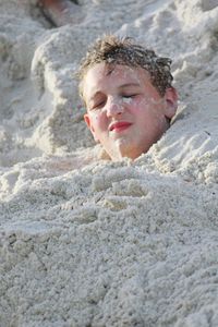 Teenage boy buried in sand