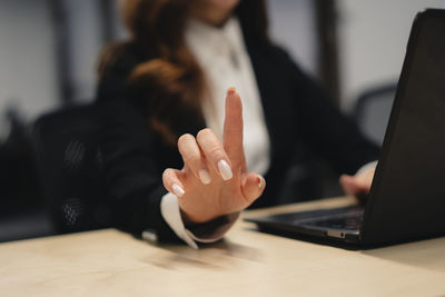 Midsection of woman using laptop at table