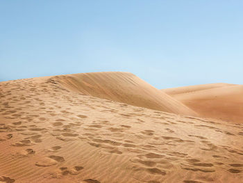 Sand dunes in desert against clear sky