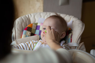 Cropped hand of woman feeding food to baby boy at home