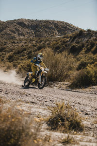 Male biker riding motorcycle at desert during sunny day