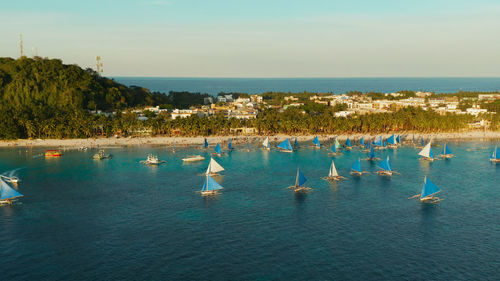 Topical white beach from above at sunset with tourists and hotels and sailing boats on boracay