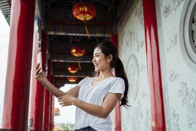 Woman using smart phone while standing in corridor