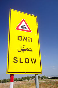 Low angle view of road sign against clear blue sky