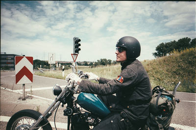 Man riding motorcycle on road against sky