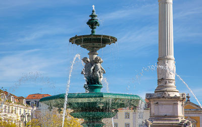 Statue of fountain against building in city