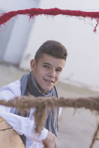 Portrait of teenage boy standing by large spool on footpath