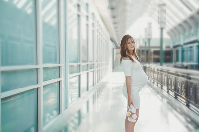Side view of pregnant woman standing in corridor