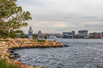 City at waterfront against cloudy sky