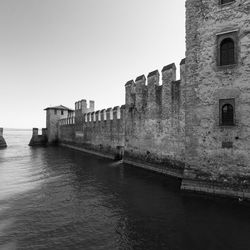 Buildings by sea against clear sky