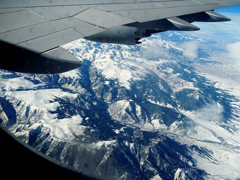 Cropped image of airplane wing over mountains