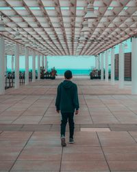 Full length rear view of boy walking indoors