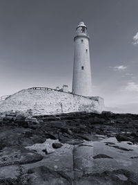 Lighthouse by sea against sky