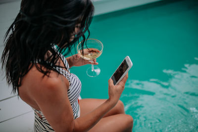 Midsection of woman using mobile phone in swimming pool