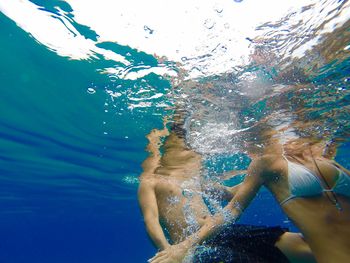 Midsection of friends swimming in sea