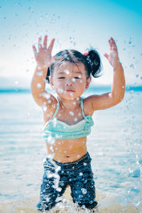Cute girl splashing water at seashore