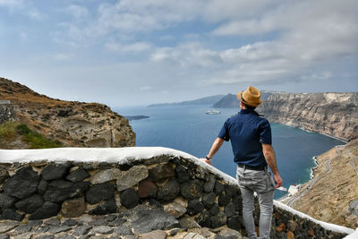 Man standing on rock looking at mountain against sky