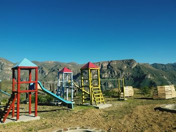 View of playground against clear blue sky