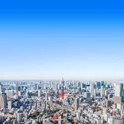 Aerial view of buildings in city against blue sky