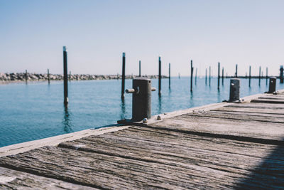 Wooden posts on pier over sea against clear sky