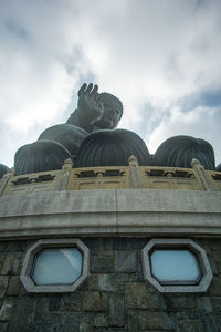 Low angle view of statue against building against sky