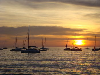 Sailboats sailing on sea against sky during sunset