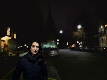 Portrait of woman standing on road in city at night