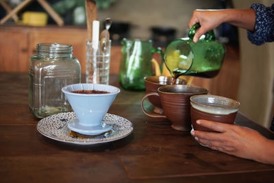 Cropped image of person holding tea cup on table