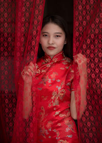 Portrait of cute girl standing against red wall