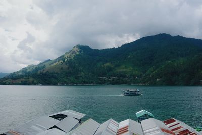 Scenic view of sea by mountains against sky