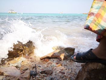 Low section of person at beach against sky