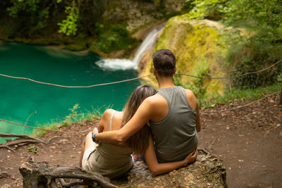 Rear view of couple sitting on rock