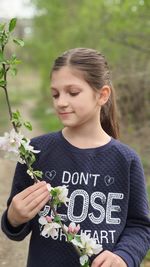 Close-up of girl holding flower in park