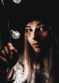 Close-up portrait of young woman by illuminated light