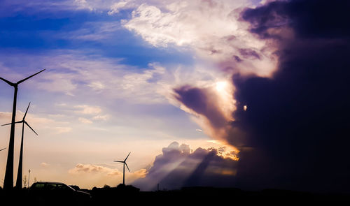 Wind turbines on silhouette landscape against sky