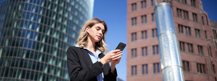 Businesswoman talking on mobile phone while standing against building