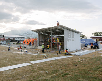 People at construction site by buildings in city against sky