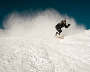 Man snowboarding on snowy land against clear sky