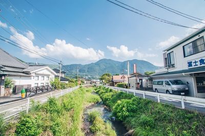 Panoramic view of railroad tracks by buildings in city against sky