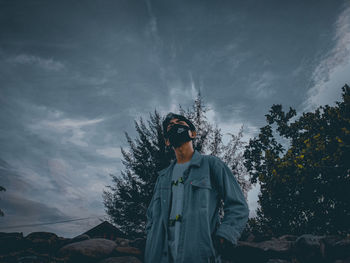 Man standing by tree against sky