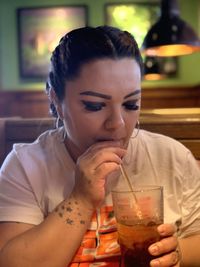 Woman drinking iced tea in glass at restaurant