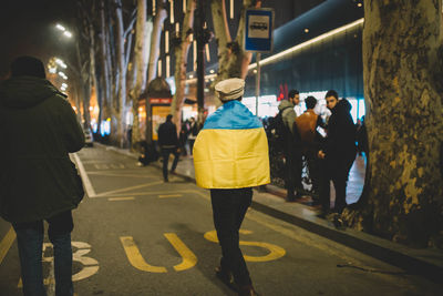 Rear view of man with ukrainian flag walking on street