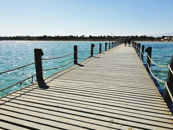 Wooden pier on sea against clear sky