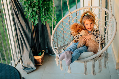 Portrait of little girl, dog sitting on sofa at home
