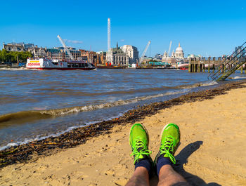 View from the sand beach on the south bank of river thames london showing sunbathing feet in sun 