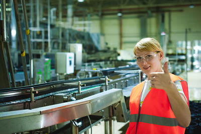 Portrait of woman in protective eyewear gesturing at factory