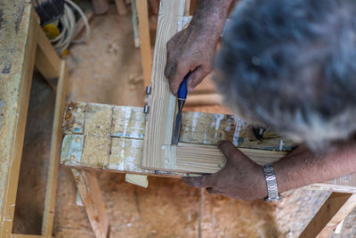 Top view of an adult man using hand tools while working on wood. 