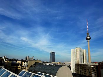 Communications tower in city against sky